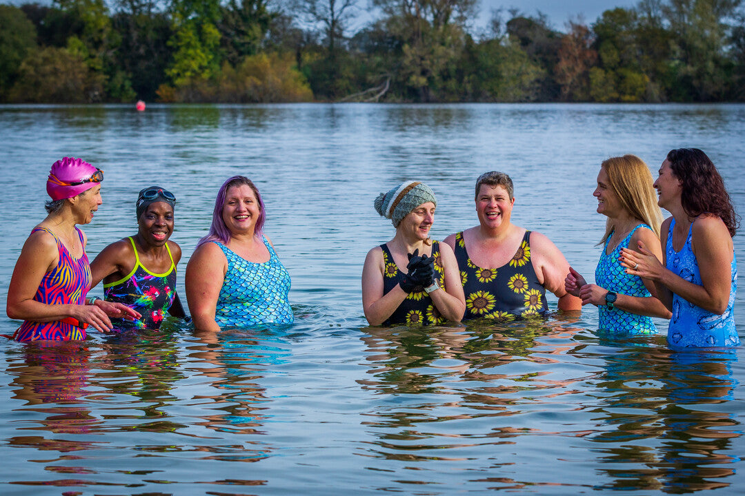 A group of women huddle around in the cold water wearing their Zoggs thermal silver lined swimming costumes during their wild swims
