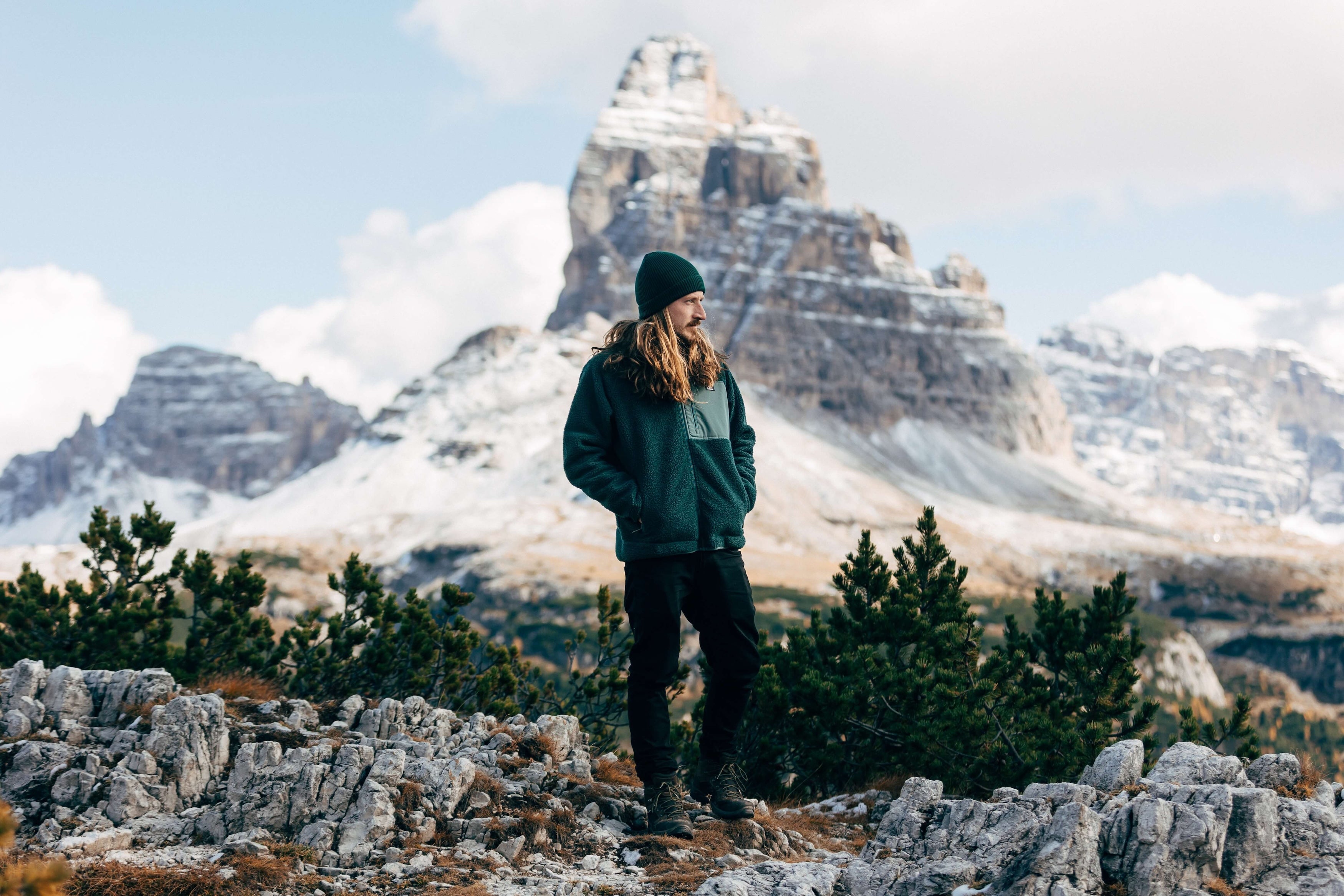 A man wearing the new Bleubird Sherpa fleece in green tracks across a mountain range.  