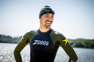 Swimmer standing by the water wearing a predator pro wetsuit.