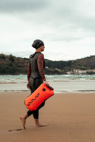 Orca wetsuit being worn for an open water swim by a triathlete holding a tow float. 