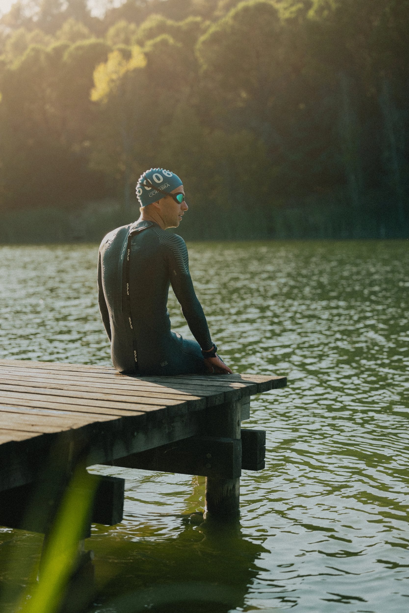 Triathlete sitting on a pontoon wearing his Orca Apex Flow wetsuit before an open water swim 