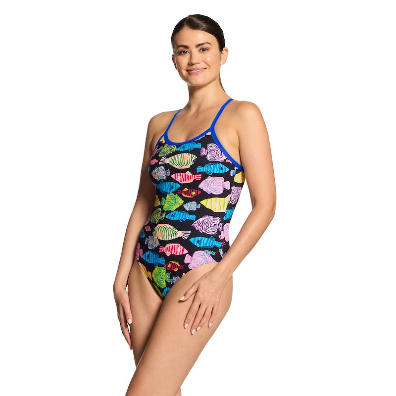 Woman wearing a colorful fish-patterned swimsuit desingned by Zoggs on a white background