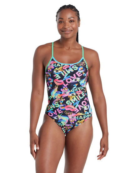 Woman wearing a colourfull Zoggs swimsuit with text and graphics on a white background.
